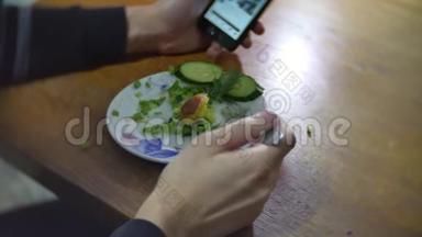 男人用洋葱和迪尔智能手机吃土豆，互联网社交媒体。 传统的俄罗斯料理在室内